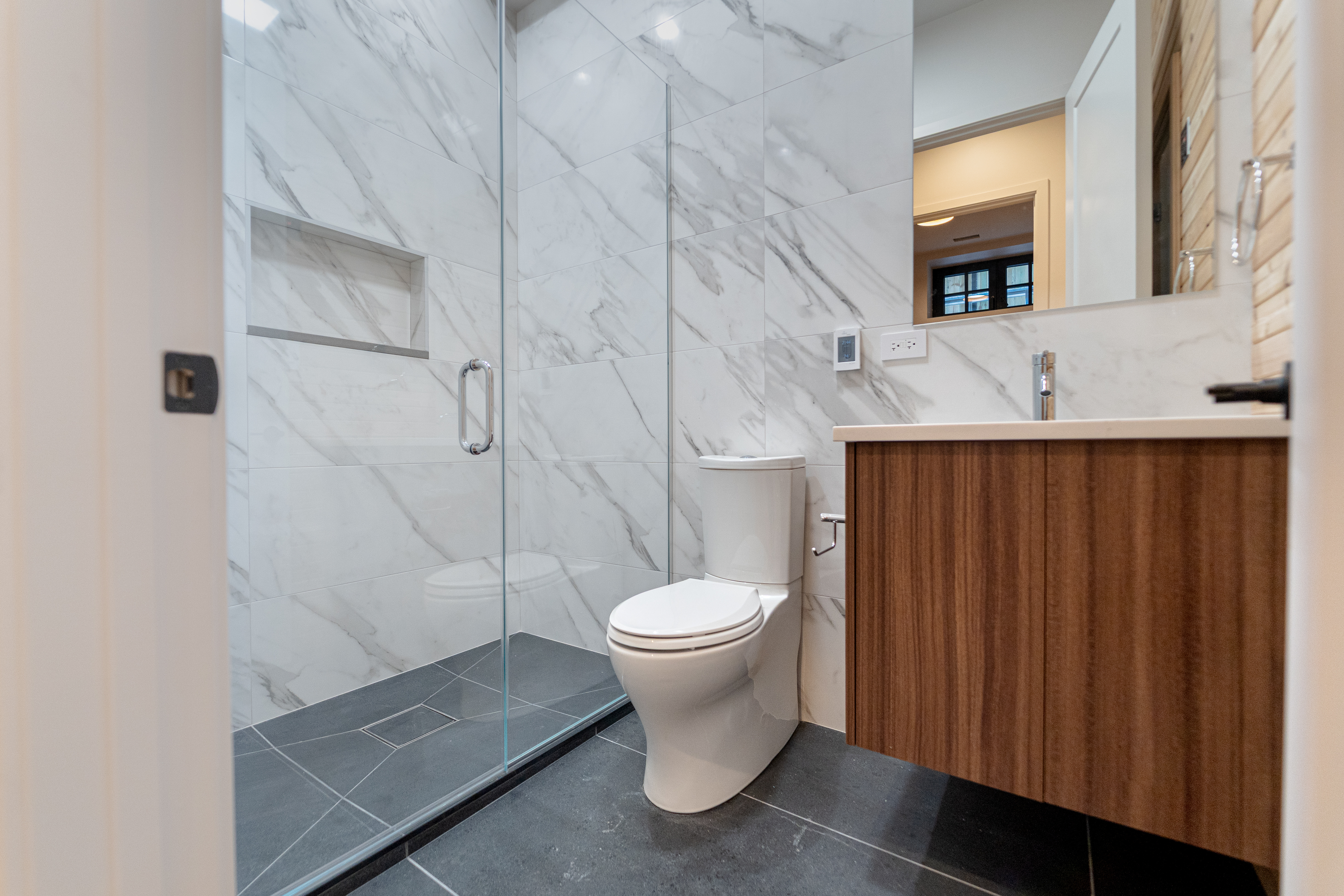 Bathroom with marble shower and walnut vanity