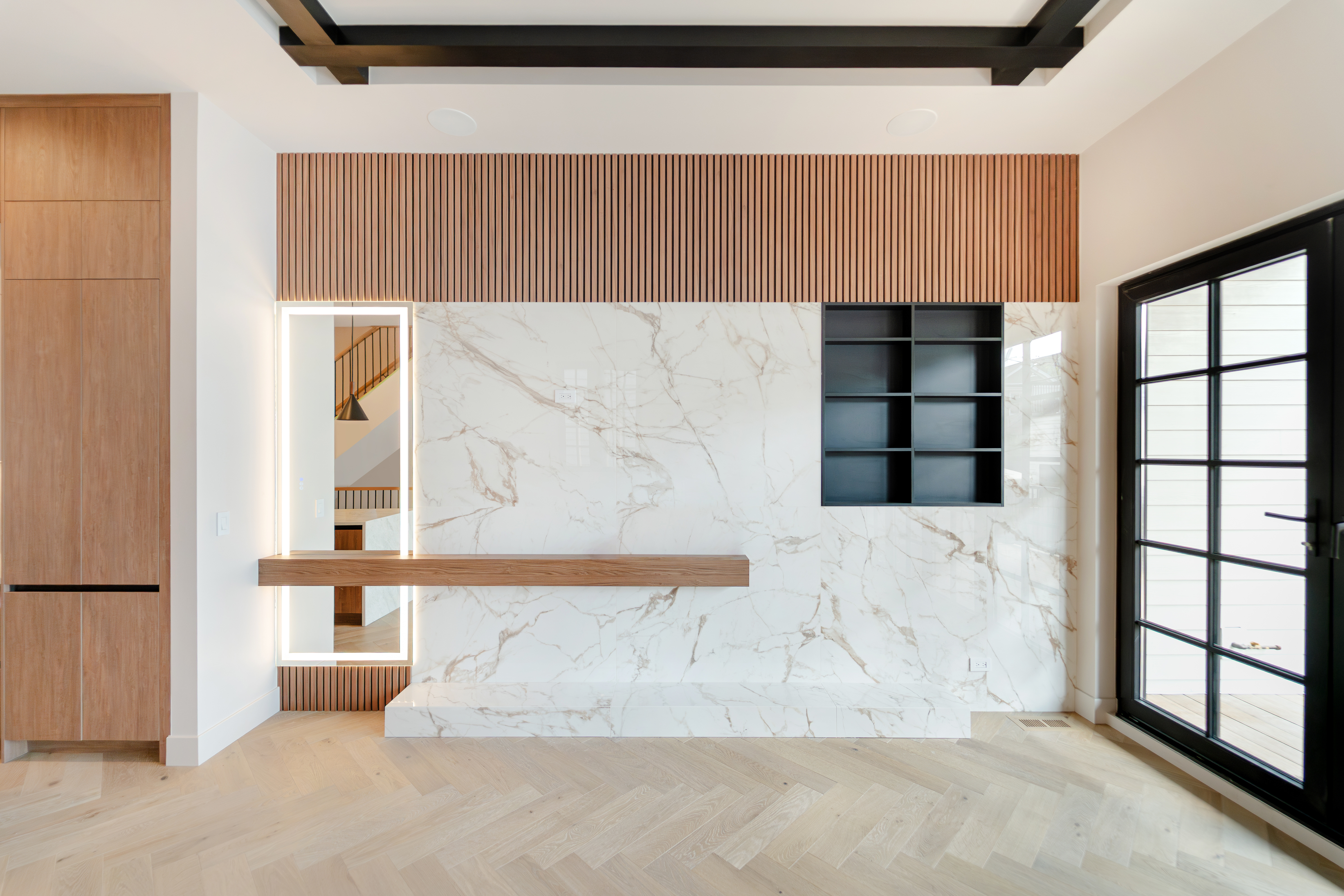 Marble fireplace wall beside black-framed doors