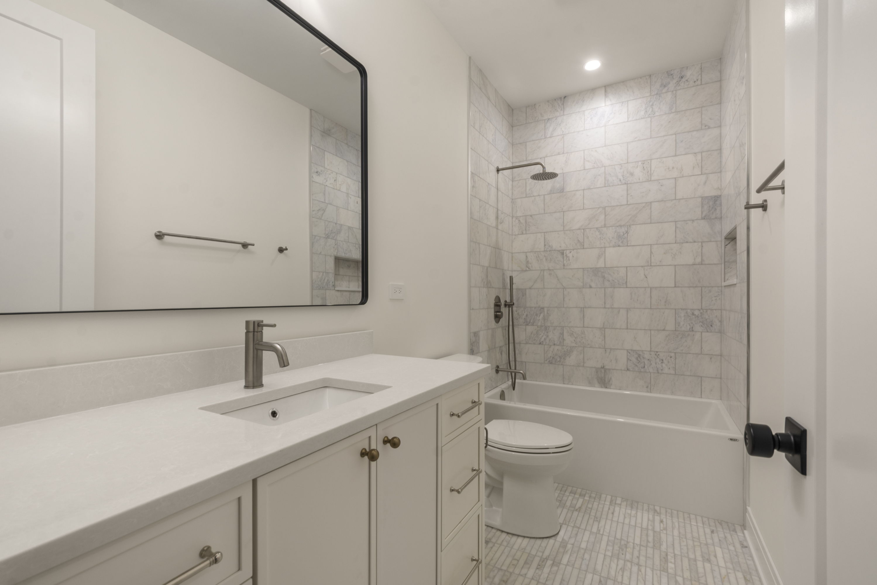 Jack-and-Jill bathroom with white vanity and tiled tub surround