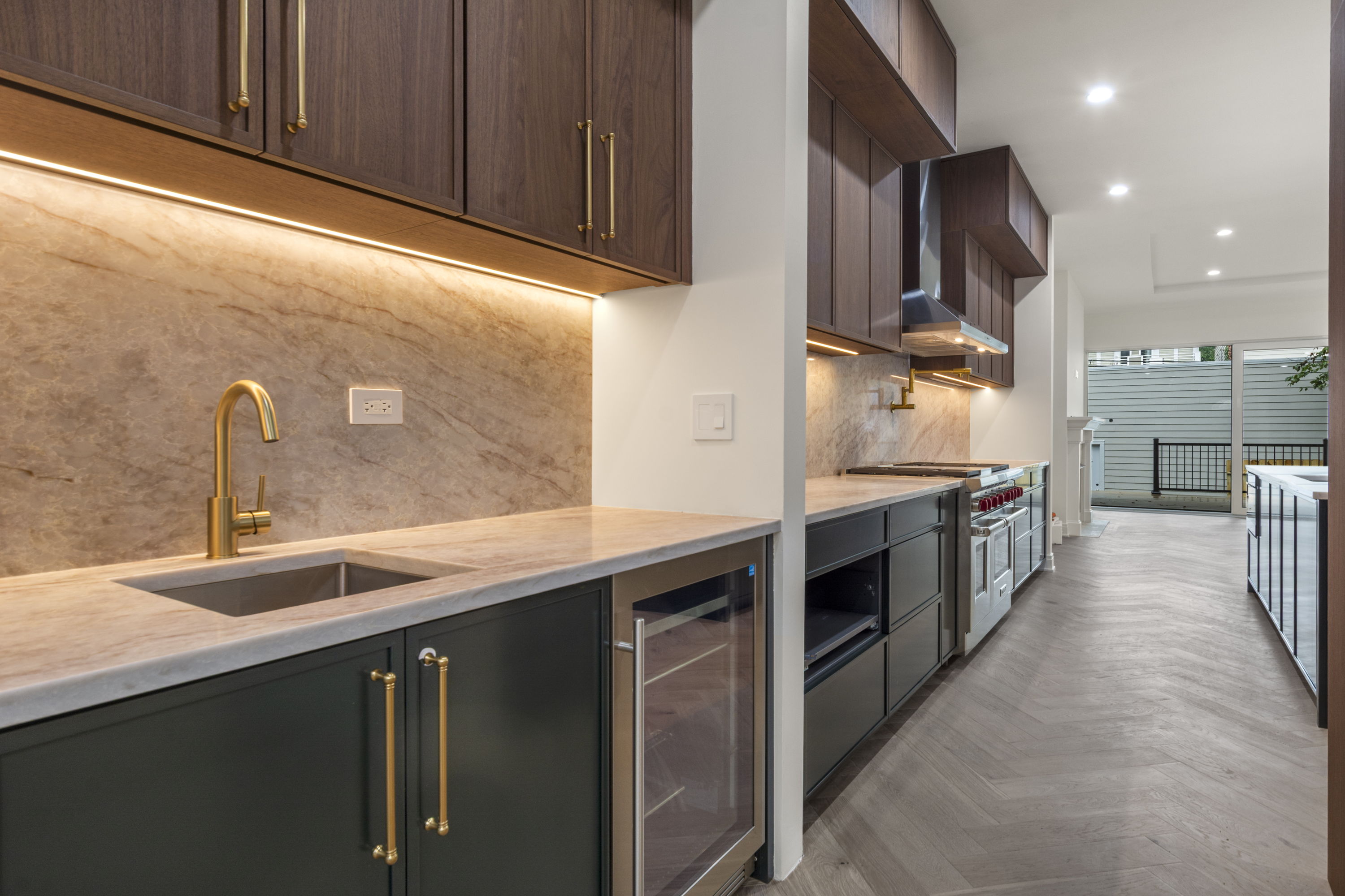 Butler's pantry with walnut cabinetry, brass faucet, and beverage refrigerator
