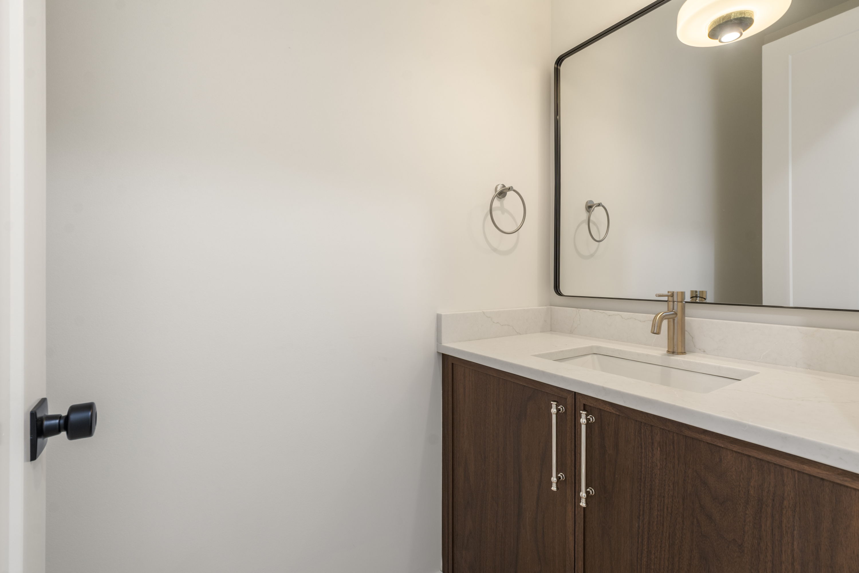 Powder room with walnut vanity and large framed mirror