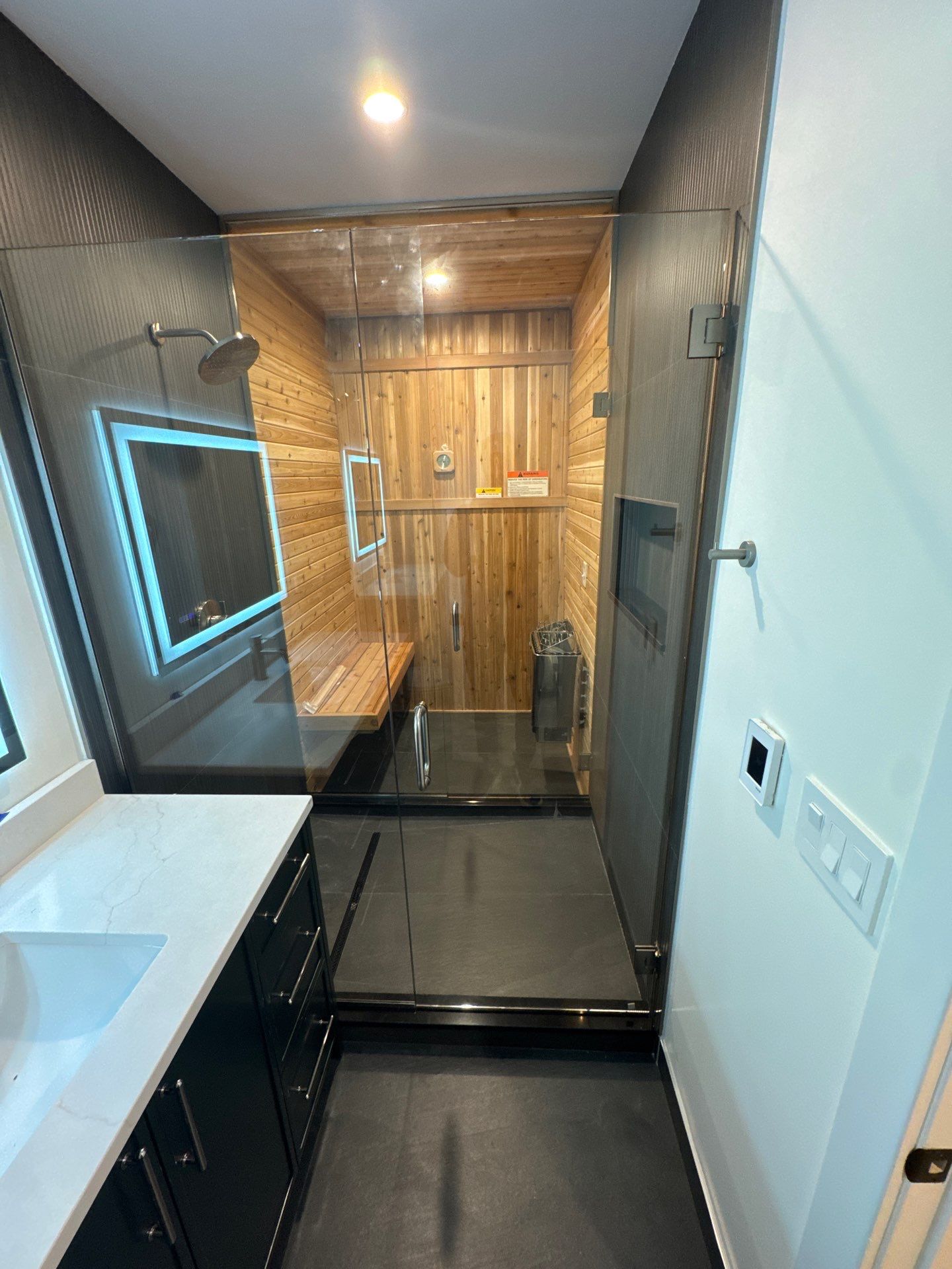 Glass-enclosed shower beside a wood-lined sauna